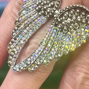 Size 8 Angel Wing Statement Ring with crystal rhinestones. Made of alloy, measures 3x4x2 cm, 13 oz. Trendy and stylish, perfect for daily wear or special occasions. A must-have accessory for those who love bold, unique jewelry.