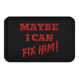 May include: Black rectangular patch with the embroidered phrase "MAYBE I CAN FIX HIM!" in red thread. The patch has a black border, designed to be sewn or ironed onto clothing or accessories.