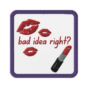 May include: Embroidered patch with a white background, a purple border, and the text "bad idea right?" in red. The patch features three red lip imprints and a red and black lipstick.