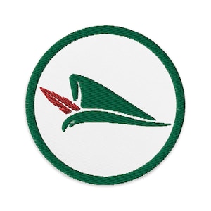 May include: Embroidered patch featuring a green and red design within a white circle, framed by a green border. The design depicts a stylized green hat with a red feather, likely a symbol or emblem.