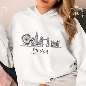 Puede incluir: Sudadera blanca con un dibujo de línea negra del horizonte de Londres, que incluye el Big Ben, el London Eye y el Tower Bridge. El texto "London" está escrito debajo del horizonte.