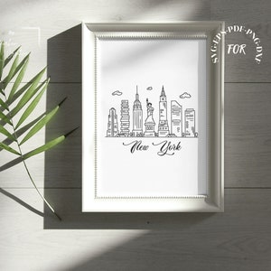 May include: A white framed print with a black and white line drawing of the New York City skyline, including the Statue of Liberty and the Empire State Building. The text "New York" is written in cursive below the skyline.