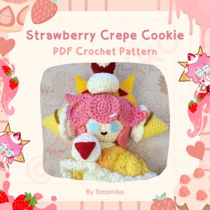 May include: A crocheted Strawberry Crepe Cookie doll with pink hair, blue eyes, and a yellow dress. The doll has a white cream topping and a red triangle on its chest. The text "Strawberry Crepe Cookie PDF Crochet Pattern" is at the top.