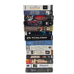 May include: A stack of vintage PC game boxes, including titles like "Collection Classique," "Exile," "Gabriel Knight 3," and "Star Trek Generations." The boxes are various colors and sizes, with game titles and logos visible.