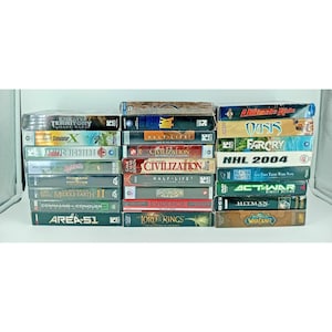 Op de afbeelding: Een verzameling pc-videogameboxen gestapeld op een witte ondergrond. Titels zijn onder meer "Enemy Territory", "Civilization", "Far Cry" en "World of Warcraft". De dozen zijn in verschillende maten en kleuren, met speltitels en logo's.