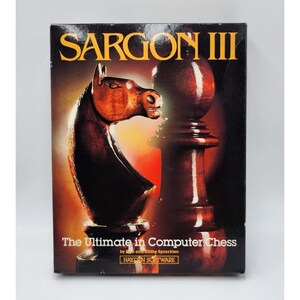 Peut inclure: Boîte de jeu d'échecs informatique SARGON III vintage. La boîte présente un cavalier et un pion d'échecs avec une finition sombre semblable à du bois sur un fond dégradé. Le texte indique "The Ultimate in Computer Chess" et "HAYDEN SOFTWARE".