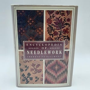 Peut inclure: Un livre à couverture rigide intitulé "Encyclopédie de la Broderie" de Thérèse de Dillmont. La couverture présente quatre panneaux avec des motifs floraux et géométriques complexes dans des tons de marron, rouge et beige, sur fond neutre.