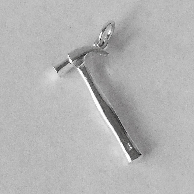May include: Silver hammer charm pendant. The hammer has a smooth, rounded head and a textured handle.