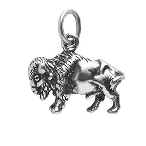 Op de afbeelding: Een zilveren bedel in de vorm van een bizon, een groot, harig wild dier. De bedel heeft een lus aan de bovenkant om aan een armband of ketting te bevestigen.