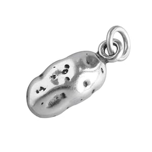 May include: A silver-colored peanut charm with a textured surface and a small loop for attaching to a necklace or bracelet. The charm is detailed with small indentations, giving it a realistic appearance.