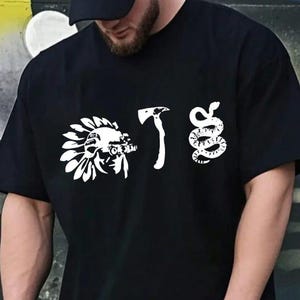 May include: Black t-shirt with white graphic designs. The shirt features a Native American headdress, an axe, and a snake. The shirt is short-sleeved and appears to be made of a soft material.