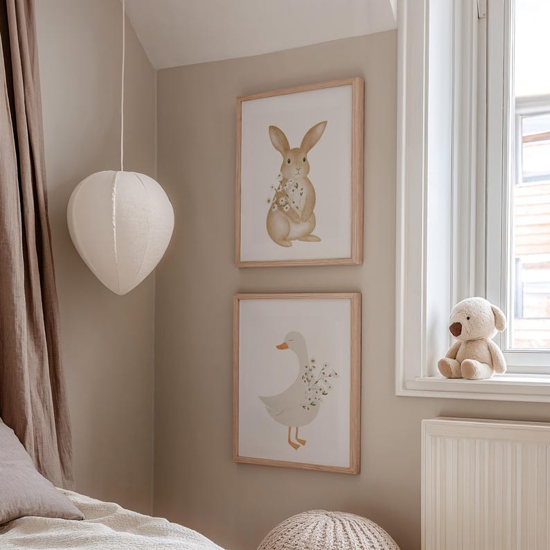 Puede incluir: Dos l&aacute;minas enmarcadas con un conejo y un pato con flores, en marcos de madera clara sobre una pared beige. Una linterna de papel blanca cuelga del techo y un peluche est&aacute; en el alf&eacute;izar de la ventana.