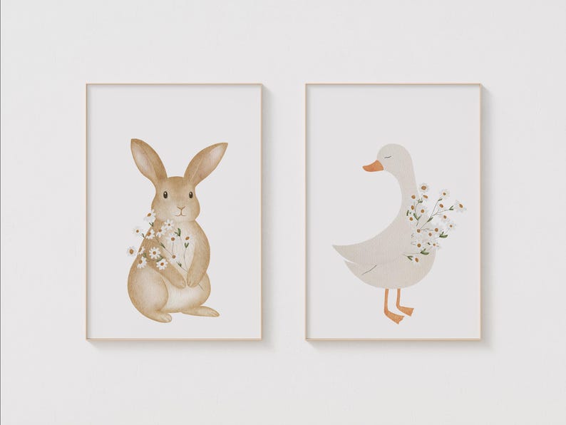 Puede incluir: Dos impresiones art&iacute;sticas enmarcadas con ilustraciones de acuarela de animales. Una muestra un conejo marr&oacute;n sosteniendo flores, y la otra un ganso blanco con pico y patas naranjas, tambi&eacute;n sosteniendo flores. Ambas sobre fondo blanco.