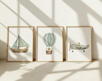 May include: Three framed watercolor prints featuring a sailboat, hot air balloon, and airplane. Each print has a light brown frame and depicts a light green and brown vehicle with a small dog. The prints are displayed against a white wall.