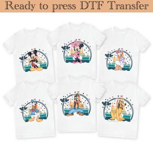 Pode incluir: T-shirts brancas com os personagens de desenhos animados Mickey Mouse, Minnie Mouse, Pato Donald, Margarida, Pateta e Pluto. Cada camisa tem um gráfico colorido com um castelo e o texto "Ready to press DTF Transfer".