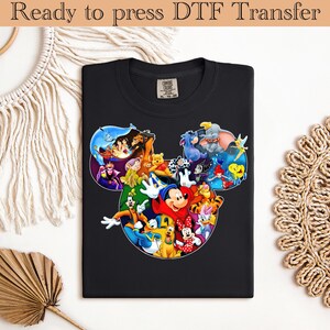 Könnte beinhalten: Schwarzes T-Shirt mit einem farbenfrohen Aufdruck von Mickey Mouse und anderen Disney-Figuren, angeordnet in der Form von Mickey's Kopf. Der Text "Ready to press DTF Transfer" steht oben.