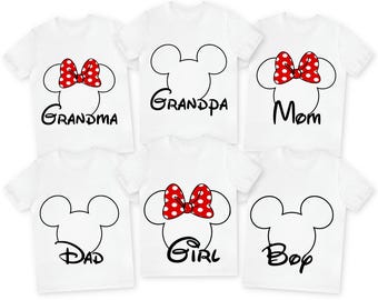 May include: Six white t-shirts with black outlines of Mickey Mouse ears and the words "Grandma", "Grandpa", "Mom", "Dad", "Girl", and "Boy" printed on them. Each shirt features a red bow with white polka dots.