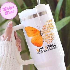 May include: White insulated tumbler with a handle, featuring an orange butterfly graphic and the text "Made Strong" with "Multiple Sclerosis Awareness". The tumbler also has the text "We don't know how strong we are until being strong is the only choice we have."