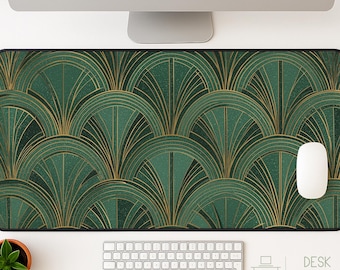 May include: A rectangular desk mat featuring a dark green background with a repeating gold fan-shaped pattern. The mat has a black stitched border and is positioned on a white surface with a white computer mouse, keyboard, and a small potted plant.