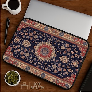 May include: Laptop sleeve with a navy blue, red, and beige floral pattern reminiscent of a Persian rug. The sleeve has a black border and the words "DESK ARTISTRY" are printed on the bottom.
