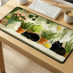Puede incluir: Alfombrilla de ratón rectangular con una ilustración de gatos y plantas. El diseño incluye un gato blanco y dos gatos negros, plantas en macetas, flores, un teclado blanco, una taza de café y un pequeño recipiente de cerámica blanco.