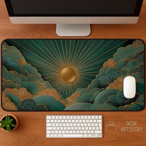 Desk mat featuring a golden sun with teal and gold clouds in an abstract art style, displayed on a wooden desk with computer, keyboard, and mouse.