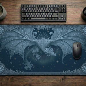 May include: A rectangular desk mat featuring a detailed illustration of a dragon with expansive wings, set against a dark blue background with star accents. The design includes ornate, symmetrical scrollwork borders and circular corner motifs.