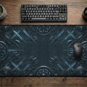 May include: A rectangular desk mat featuring a dark, intricate pattern of metallic shields, crossed battle axes, and glowing blue runic inscriptions. The mat is positioned on a wooden surface with a black computer keyboard, a black mouse, and a small potted plant.