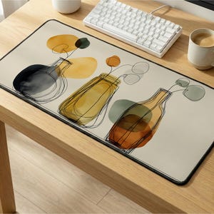 May include: A rectangular beige mousepad featuring an abstract illustration of three vases with flowers. The vases are in black, yellow, and orange, with black outline details. The mousepad has a black border and is on a wooden desk.