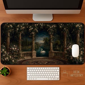 May include: A decorative desk mat featuring a romantic landscape with a swan on a lake, framed by classical columns and floral arches. The mat has a dark background and a circular design in the foreground. A white mouse and keyboard are also visible.