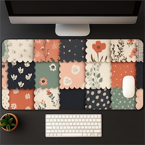 May include: A rectangular desk mat with a patchwork design featuring floral patterns in shades of orange, navy, green, and pink. A white mouse and keyboard are visible on the black surface.