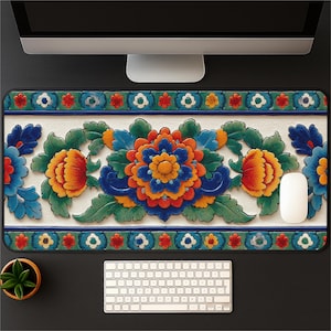 Puede incluir: Alfombrilla de ratón rectangular con un diseño floral. El diseño presenta una gran flor central en tonos naranja, azul y amarillo, rodeada de hojas verdes. El borde tiene un patrón repetitivo de flores y formas geométricas.