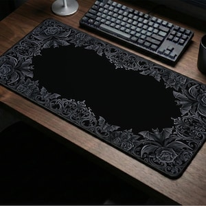 May include: Black rectangular mouse pad with a decorative border featuring roses and bats. The center is solid black. A keyboard, mouse, and mug are on a wooden desk.