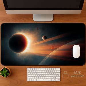Puede incluir: Alfombrilla de escritorio rectangular con un diseño espacial que muestra planetas, anillos y un efecto de eclipse solar en tonos naranja, rojo y negro. Un ratón de ordenador blanco está a la derecha. El texto "DESK ARTISTRY" está en la esquina inferior derecha.