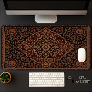 May include: A rectangular desk mat with a Halloween-themed design. The mat features a central floral pattern in shades of brown, black, and gold, with jack-o'-lanterns in each corner. A computer mouse and keyboard are visible.