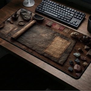 May include: A desk setup with a large mouse mat featuring a vintage parchment design. The mat is surrounded by a keyboard, a black mug, a mouse, and decorative items like stones and a rolled scroll. The overall aesthetic is rustic and vintage.