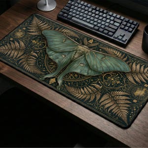 May include: A rectangular desk mat featuring a large, pale green luna moth centered over a dark background. The design includes intricate gold-colored fern fronds and geometric circular patterns surrounding the moth on a deep black surface.