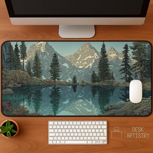 Pode incluir: Tapete de secretária retangular com uma paisagem de montanha e lago, refletindo as árvores e os picos. O tapete tem uma borda preta e um rato de computador branco está à direita. O texto "DESK ARTISTRY" está no canto inferior direito.