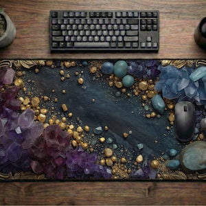 May include: A rectangular mousepad featuring a dark blue and gold design with amethyst and crystal accents. A black keyboard, mouse, and coffee cup are on a wooden surface. A small potted plant is also visible.