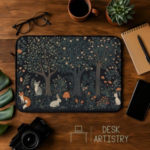 May include: Laptop sleeve featuring a forest scene with trees, mushrooms, and animals like foxes and rabbits. The design is in dark green, brown, and orange tones. The text "DESK ARTISTRY" is at the bottom.