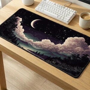 May include: A rectangular mousepad featuring a night sky scene with a crescent moon, stars, and fluffy clouds. The design includes a forest silhouette and a small cabin. The mousepad is on a wooden desk.