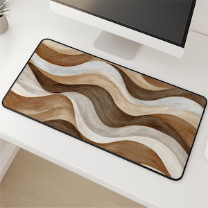 May include: A rectangular desk mat with a wavy pattern in shades of brown, tan, and white. The mat has a black border and is designed to sit under a computer and mouse. The design resembles flowing hair or wood grain.