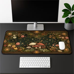 May include: A rectangular desk mat featuring a dark forest scene with various mushrooms, colorful wildflowers, and glowing golden circular accents along the border. The mat is positioned on a desk with a computer monitor, keyboard, and white mouse.