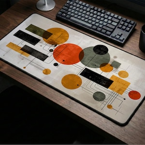 May include: Rectangular mouse pad with an abstract geometric design. The design features orange, yellow, black, and gray circles and rectangles connected by thin black lines on a light beige background. A black border frames the pad.