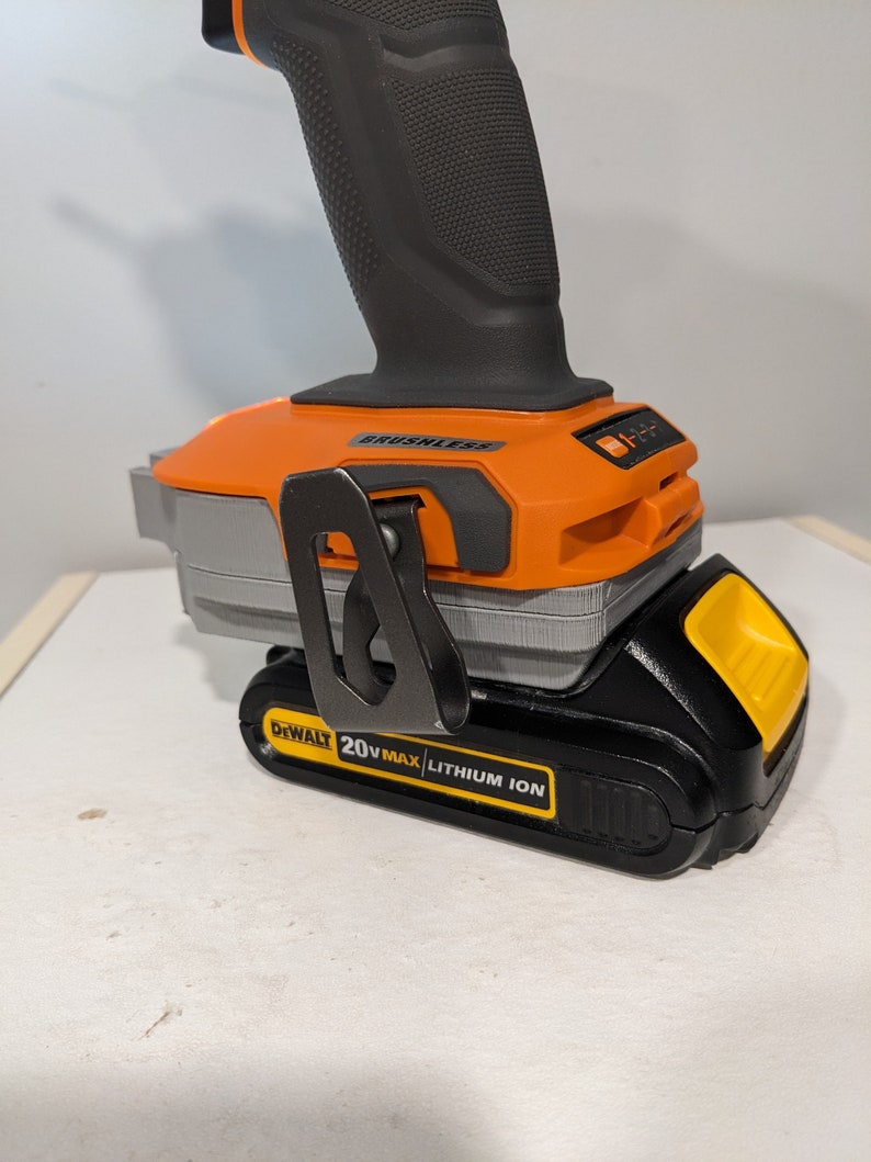 May include: A black and orange cordless drill with a 20V MAX lithium-ion battery. The drill has a black handle and a silver belt clip. The battery is labeled "DEWALT 20V MAX LITHIUM ION".