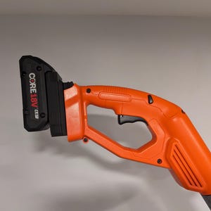 Pode incluir: Uma ferramenta elétrica sem fio laranja e preta com uma bateria preta que diz "CORE18V". A ferramenta tem um gatilho e uma alça.