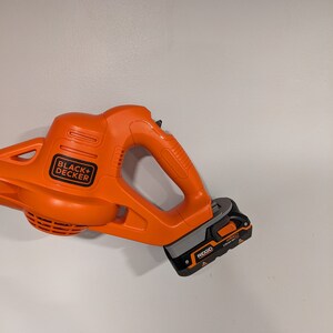 Pu&ograve; includere: Un soffiatore per foglie senza fili arancione e nero con una batteria nera etichettata "RIGID 18V Lithium Ion". Il soffiatore per foglie &egrave; prodotto da BLACK+DECKER.