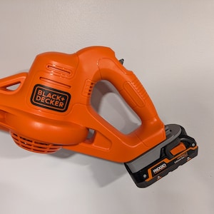 Pu&ograve; includere: Un soffiatore a batteria senza fili arancione e grigio con logo "BLACK+DECKER" nero e batteria al litio RIDGID da 18V.