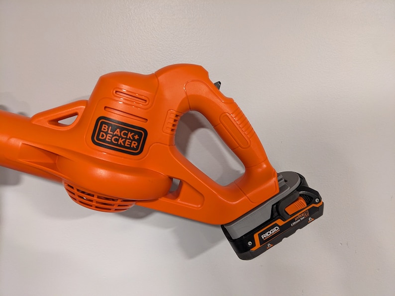 Pu&ograve; includere: Un soffiatore a batteria senza fili arancione e grigio con logo "BLACK+DECKER" nero e batteria al litio RIDGID da 18V.