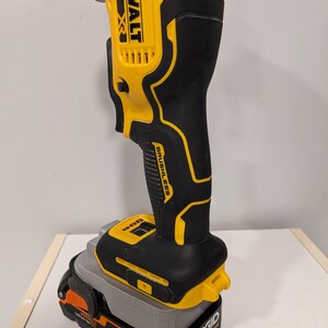 May include: A yellow and black DeWalt 20V XR cordless oscillating tool with a brushless motor is attached to a gray Ridgid 18V battery.